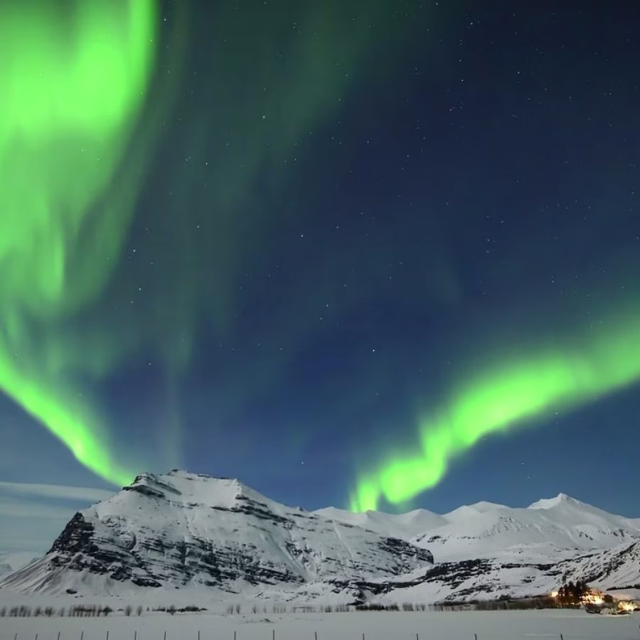 Cielo iluminado por auroras boreales en Salla, Laponia, sobre un paisaje nevado.
